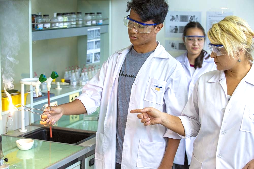 A group of people in lab coats and goggles are working in a lab.