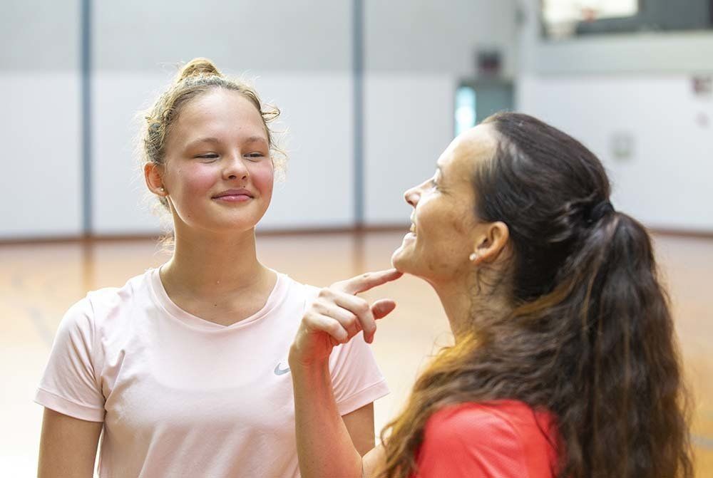 A woman is touching another woman 's face in a gym.