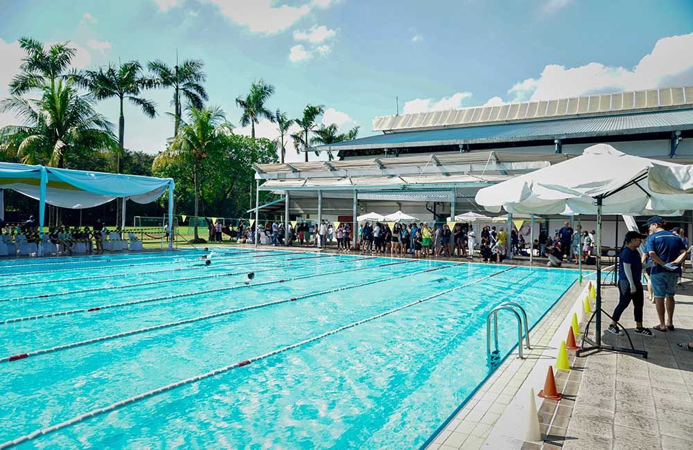 A group of people are standing around a large swimming pool.