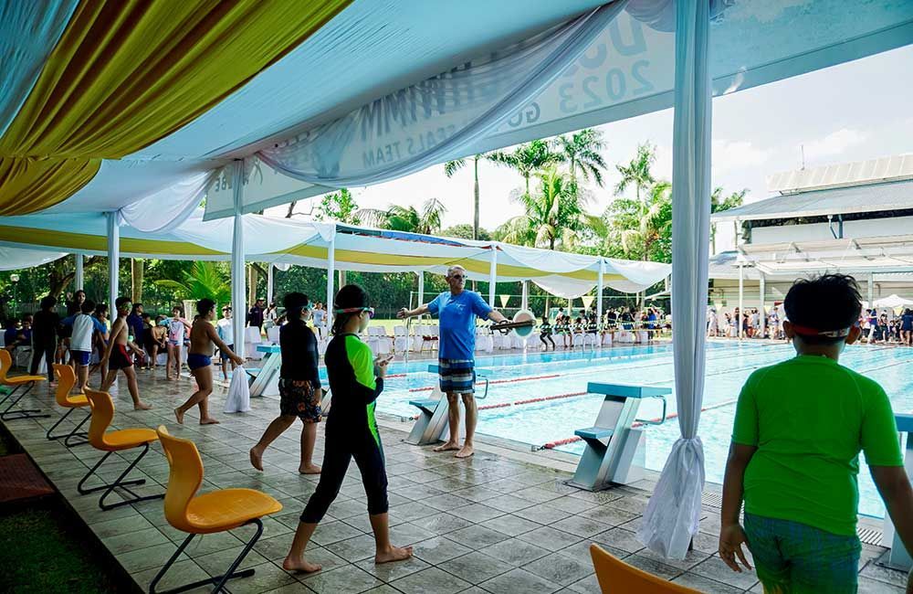 A group of people are walking around a swimming pool.