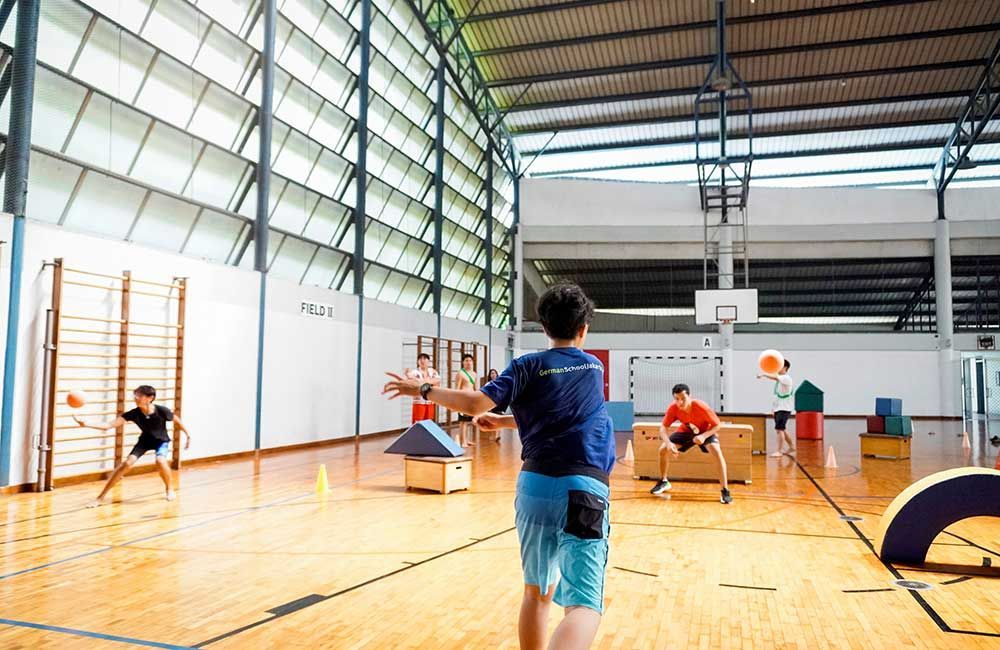 A boy is throwing a frisbee in a gym.