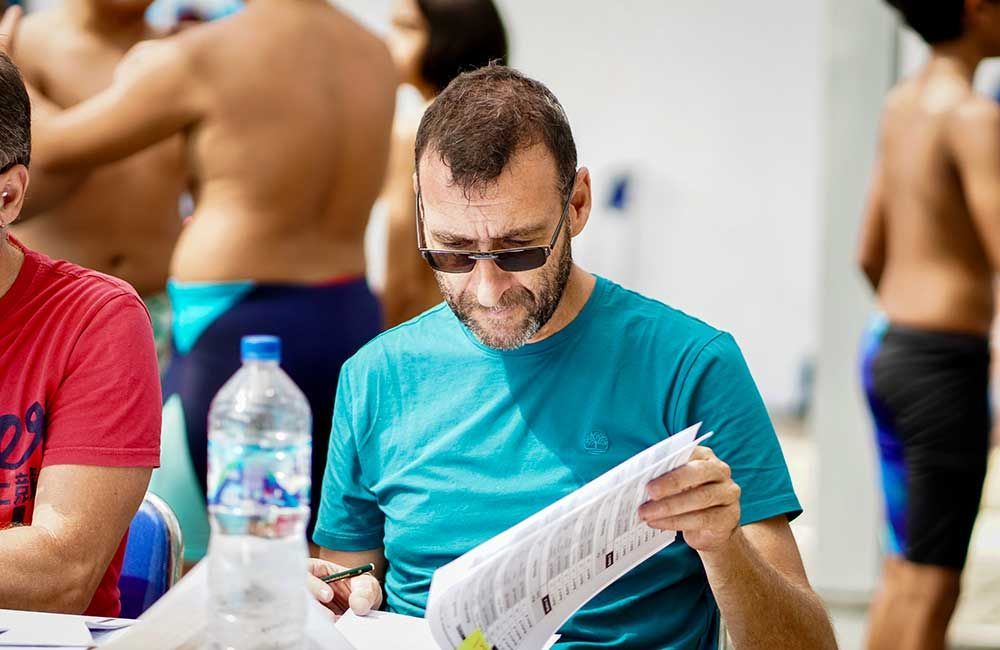 A man is sitting at a table reading a piece of paper.