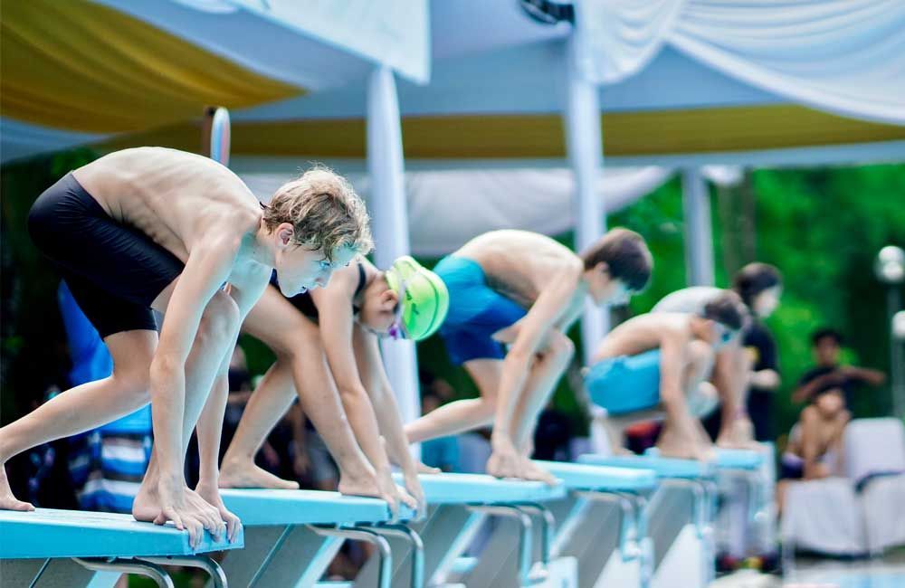 A group of young boys are getting ready to swim in a pool.