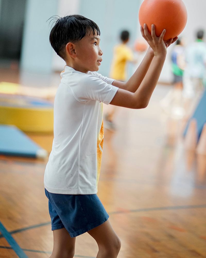 A young boy is holding a basketball in his hands on a basketball court.