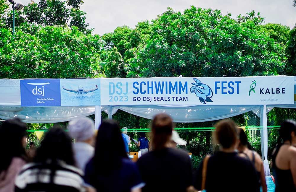 A group of people standing in front of a sign that says dsj schwimm fest
