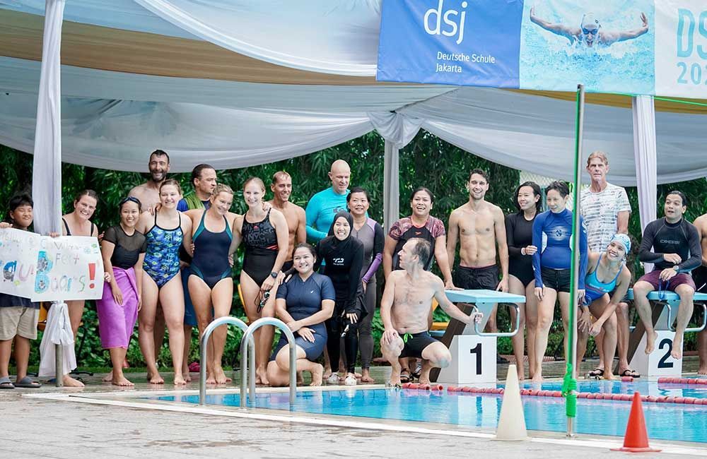 A group of people are posing for a picture in front of a swimming pool.
