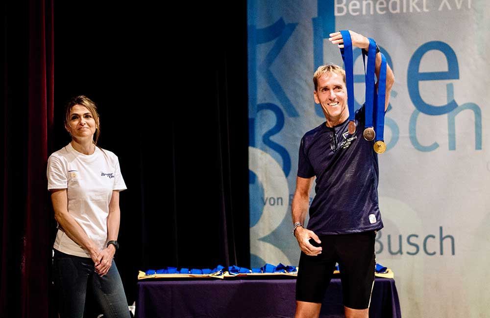 A man is holding a medal while standing next to a woman on a stage.