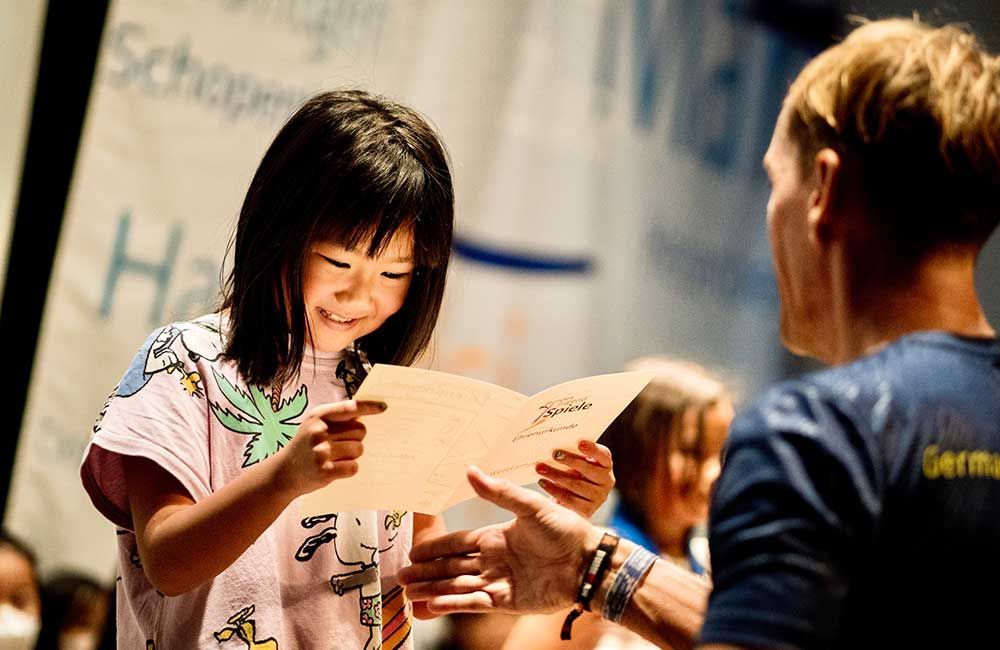 A little girl is holding a piece of paper in front of a man.
