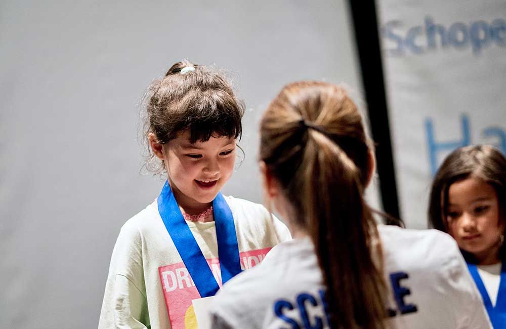 A woman is giving a medal to a little girl.
