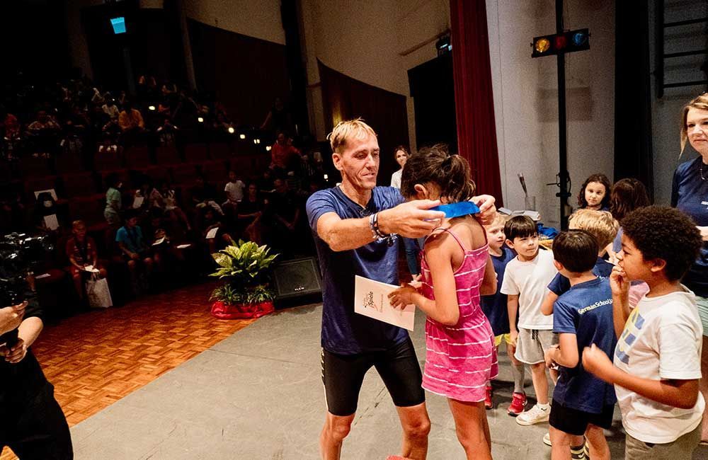 A man is giving a girl a medal on a stage.