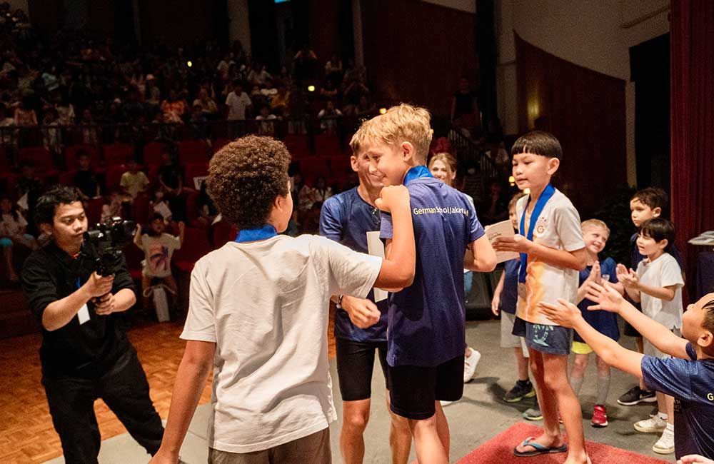 A group of young boys are hugging each other on a stage.