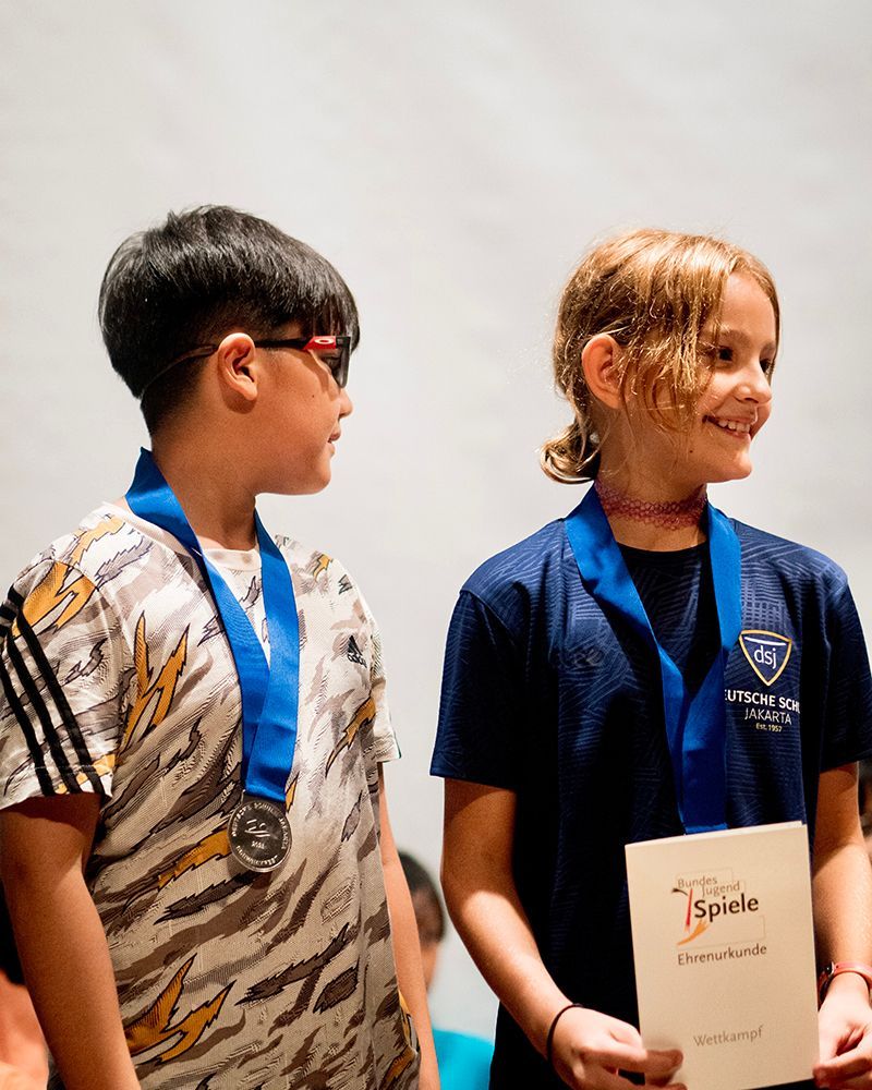 A boy and a girl are standing next to each other wearing medals.