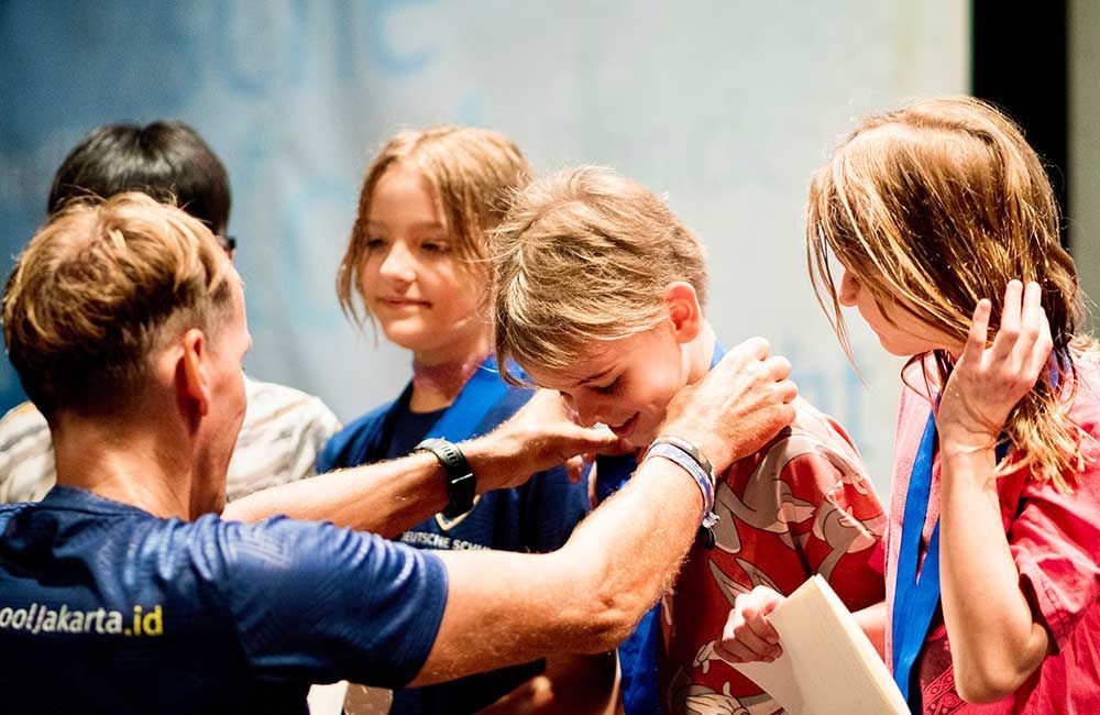 A man is putting a medal on a girl 's neck.