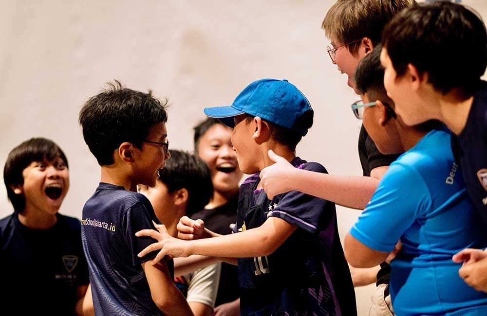 A group of young boys are hugging each other and laughing.