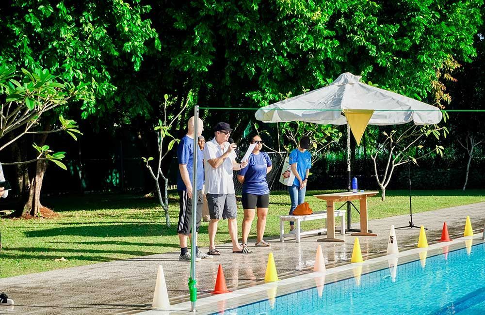 A group of people are standing next to a swimming pool.