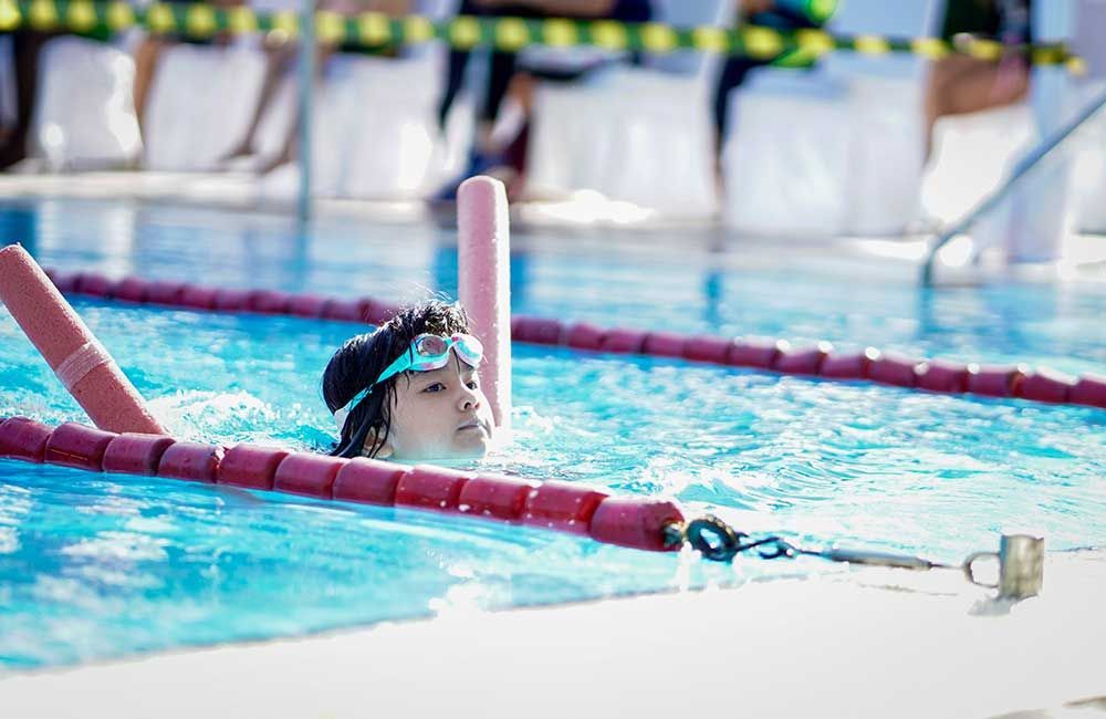 A young boy is swimming in a swimming pool.