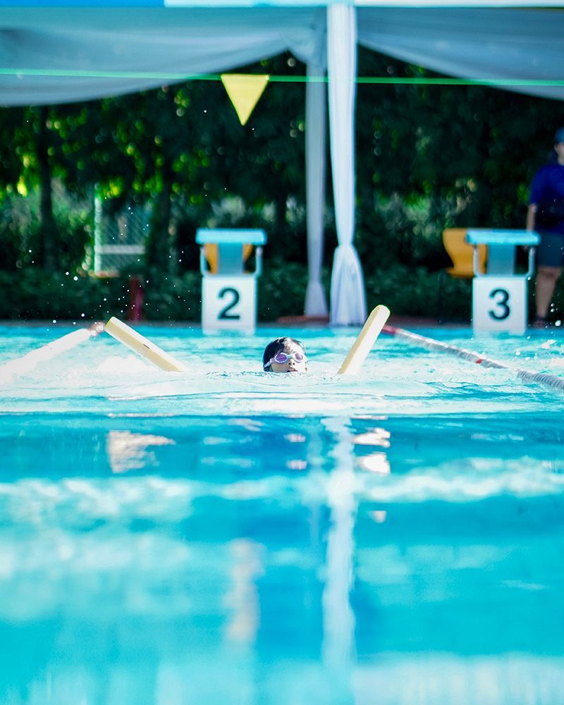 A person is swimming in a pool with a number 2 and 3 in the background.