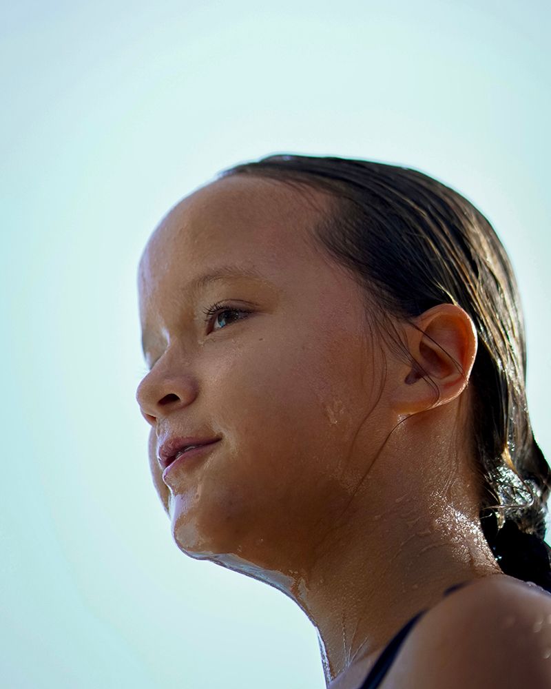 A close up of a young girl 's face with a blue sky in the background.