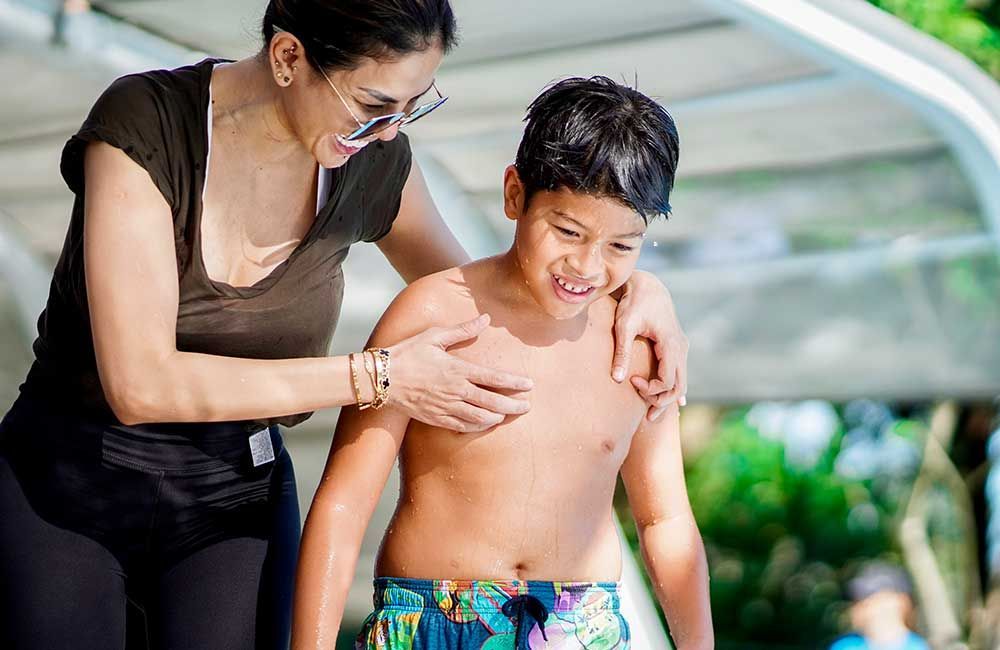 A woman is putting her arm around a boy 's shoulder.