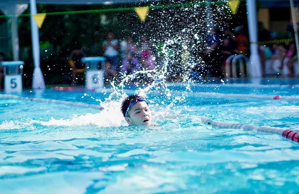 A young boy is swimming in a swimming pool.