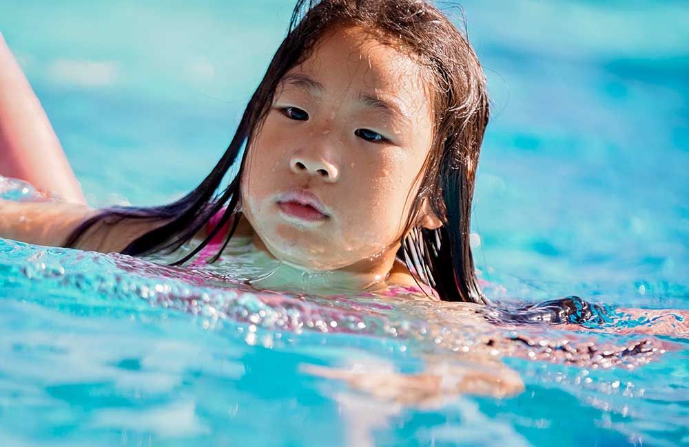 A little girl is swimming in a swimming pool.