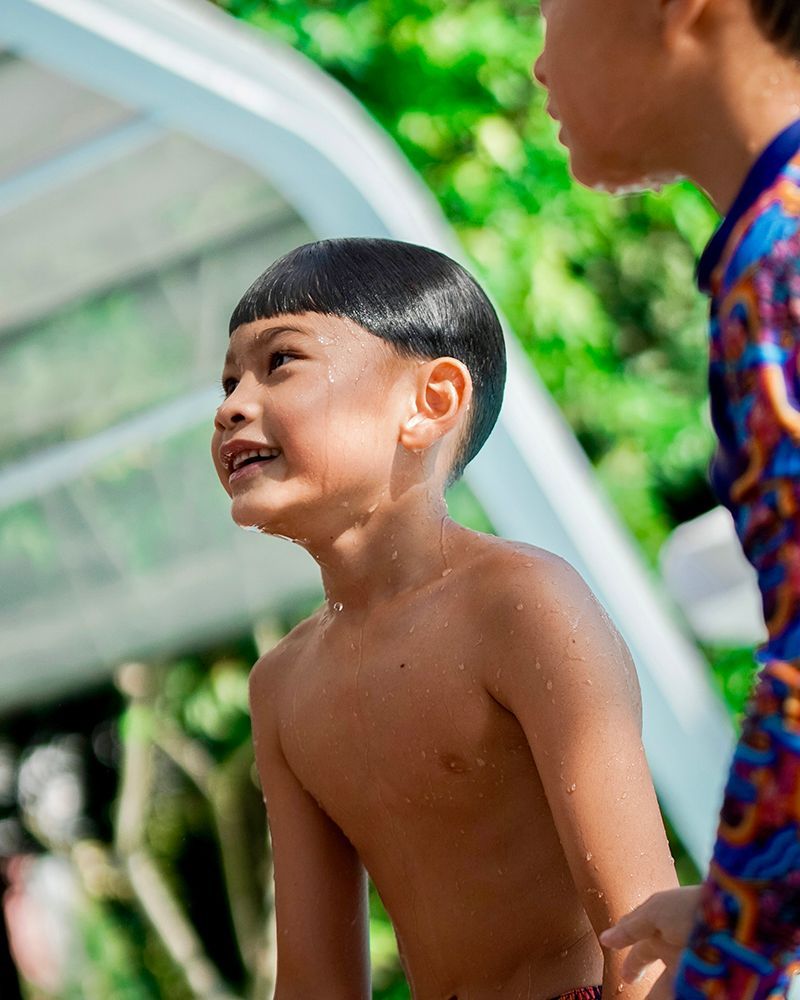 A shirtless boy is standing next to a shirtless boy in a pool.