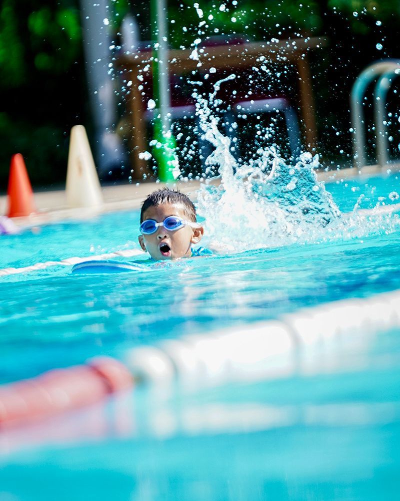 A young boy is swimming in a swimming pool wearing goggles.