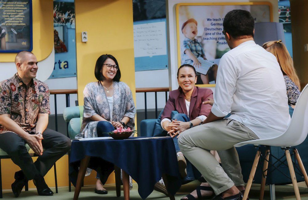 A group of people are sitting around a table talking to each other.