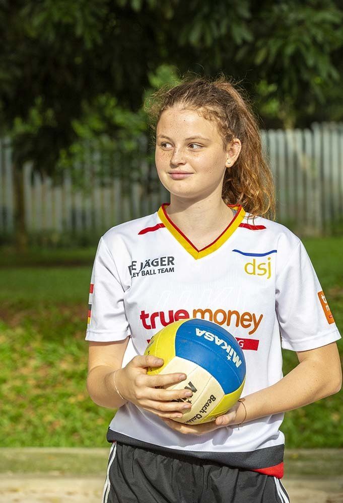 A young girl is holding a volleyball in her hands.