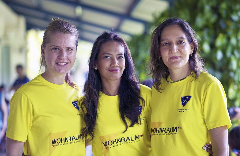 Three women wearing yellow shirts are posing for a picture.