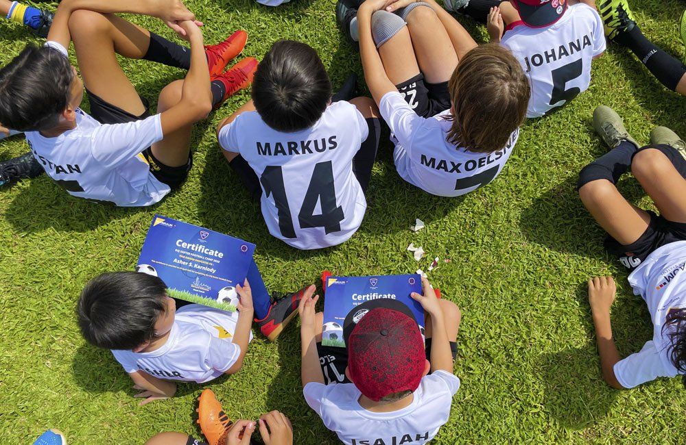 A group of young boys are sitting in a circle on a soccer field.
