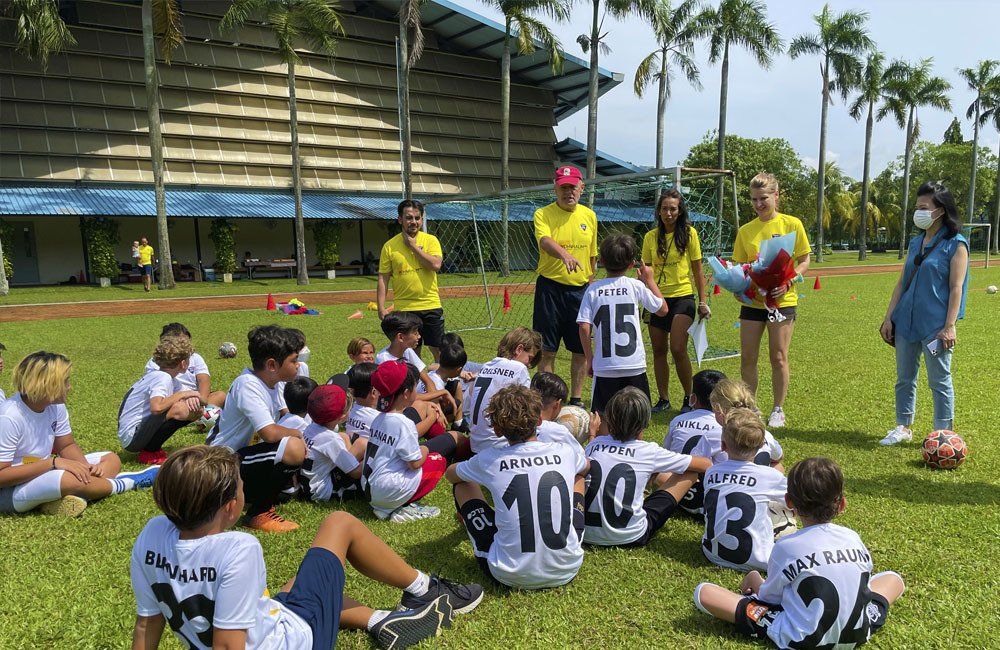 A group of children are sitting in a circle on a soccer field.