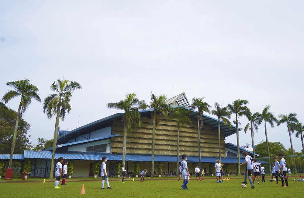 A group of people are playing soccer in front of a large building.
