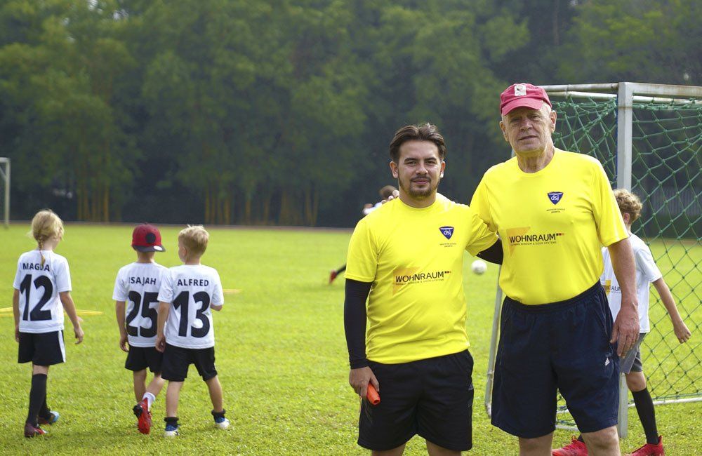 Two men in yellow shirts are standing next to each other on a soccer field.