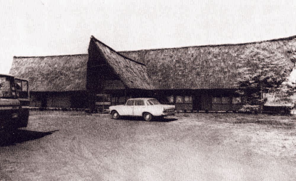 A black and white photo of a car parked in front of a building.