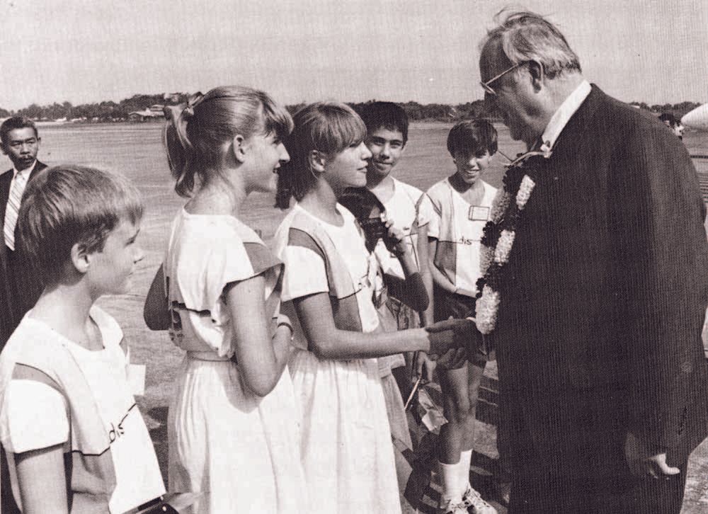 A man in a suit is talking to a group of children