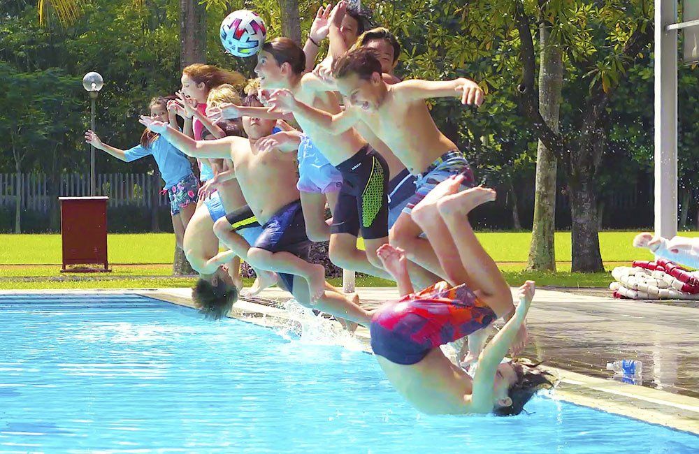 A group of children are jumping into a swimming pool.
