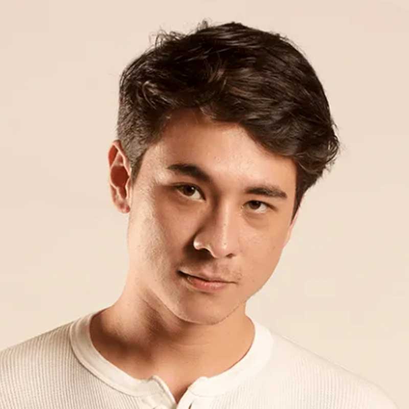 A young man is wearing a white shirt and looking at the camera.