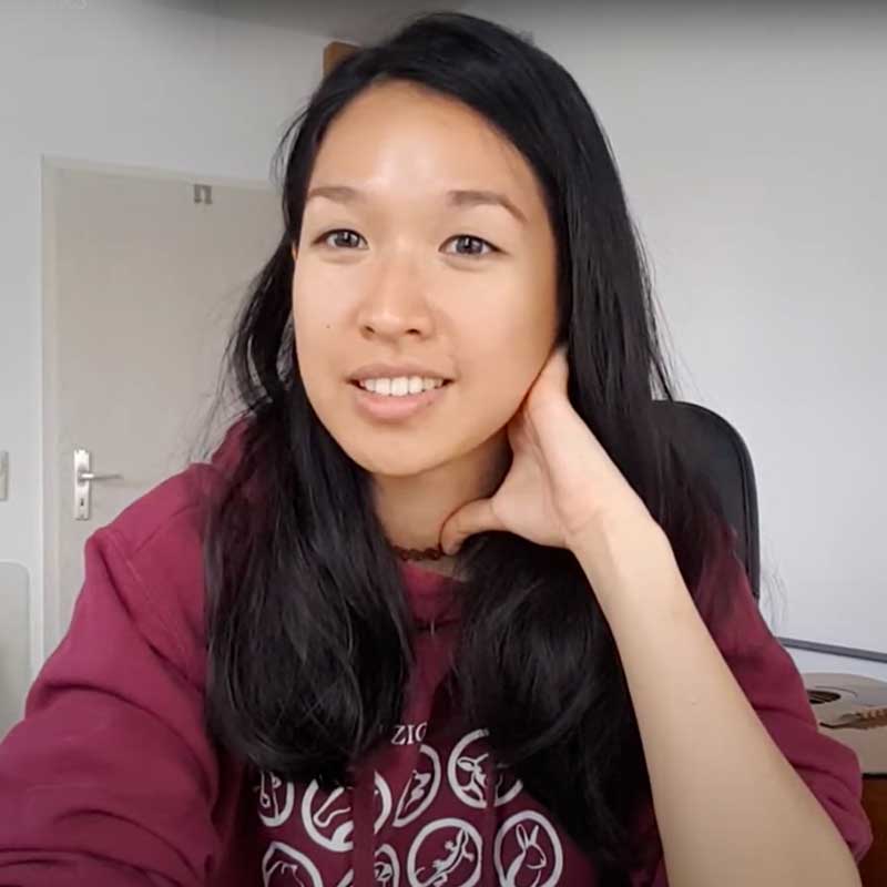 A woman with long black hair is wearing a maroon shirt