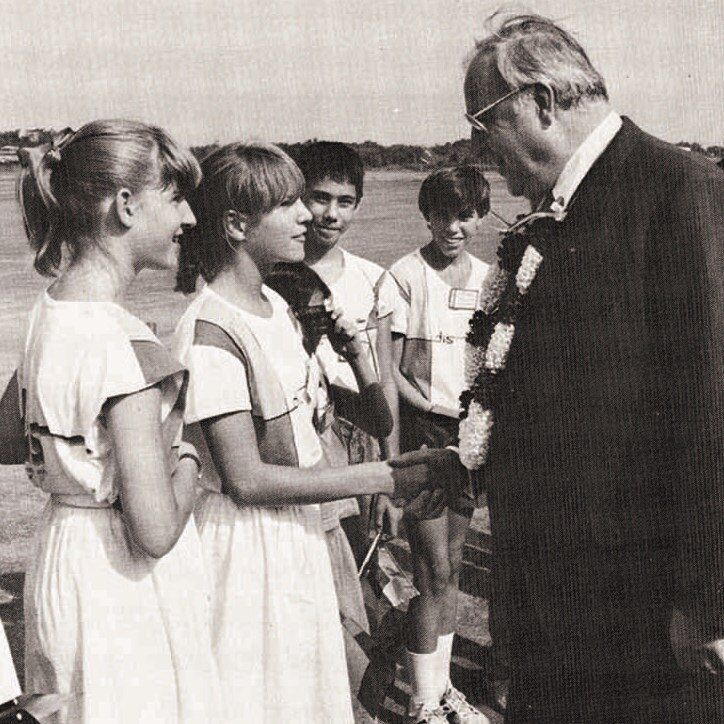 A man in a suit is talking to a group of children