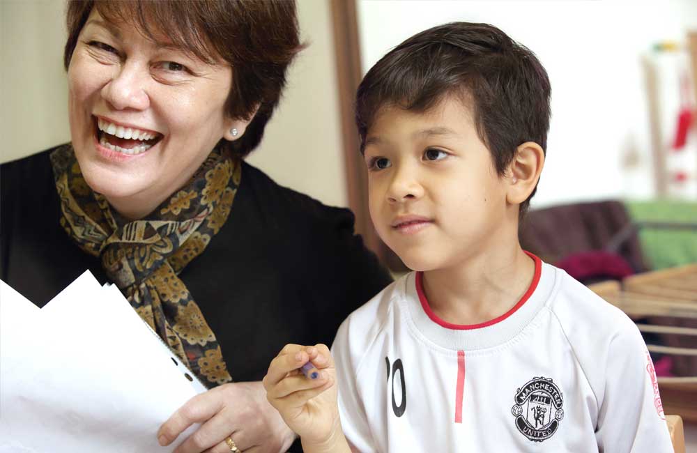 A woman is smiling while holding a piece of paper next to a young boy.