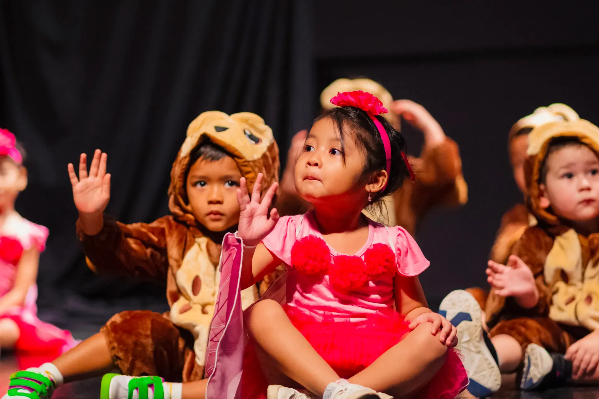 Child threading yellow strings through a board with a face cutout at a colorful indoor event