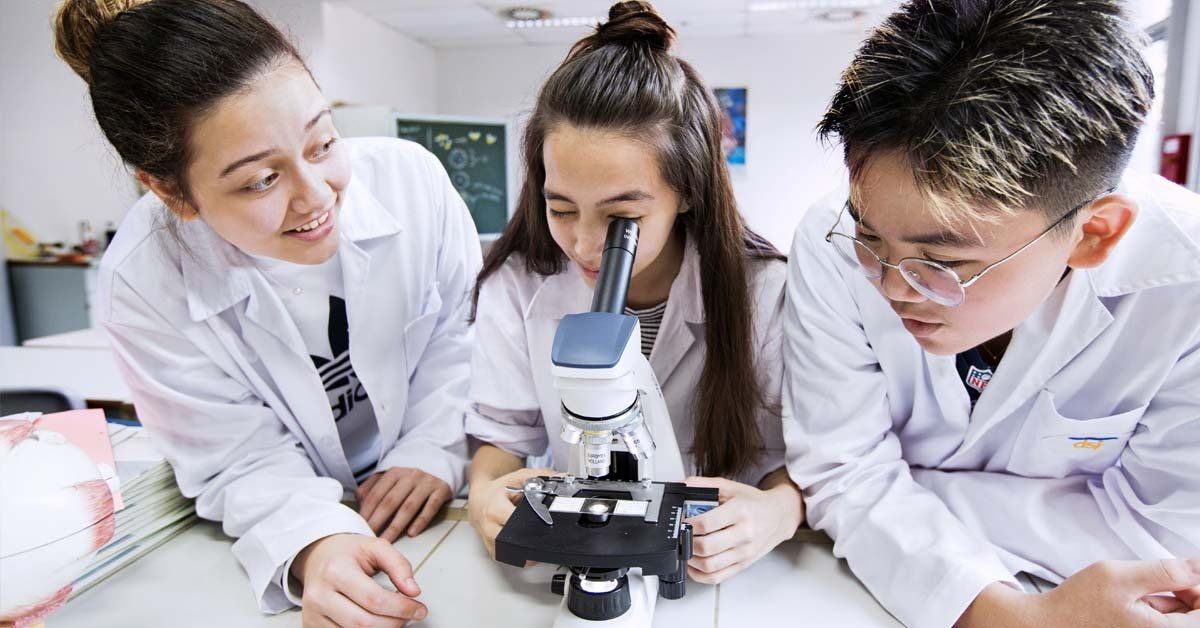 A group of students are looking through a microscope in a lab.