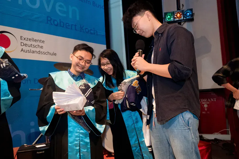 A group of people in graduation gowns are standing in front of a microphone.