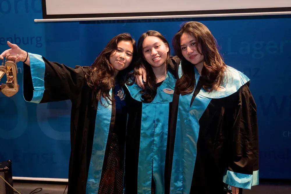 Three women in graduation gowns are posing for a picture.