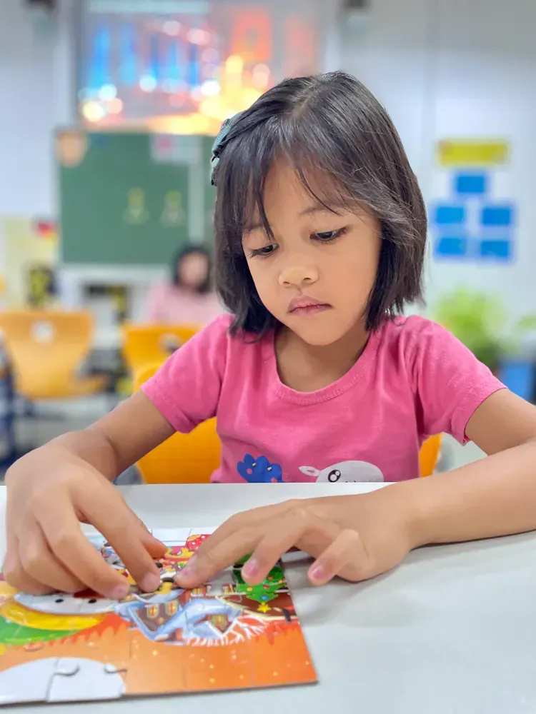 A little girl in a pink shirt is playing with a puzzle