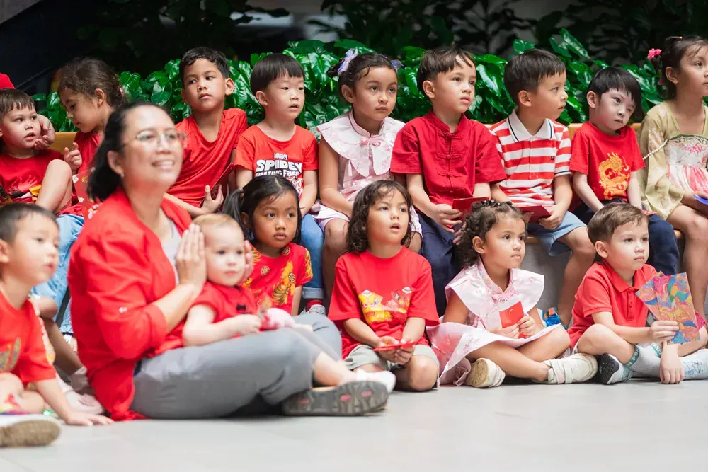 A woman is sitting on the ground with a group of children.