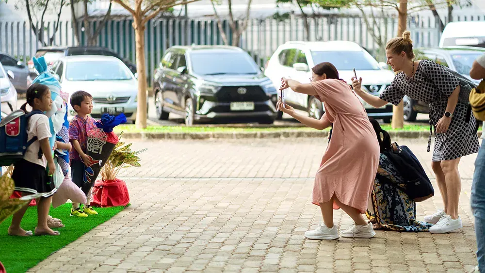 A woman is taking a picture of a little girl with a bouquet of flowers.