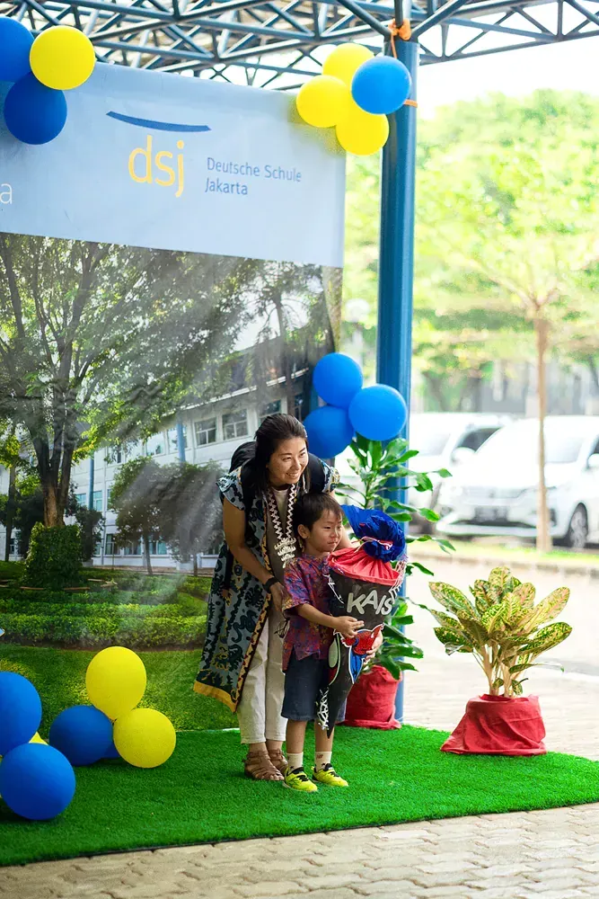 A woman is holding a child in her arms in front of balloons.