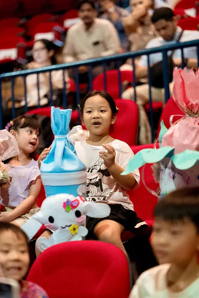 A little girl is sitting in a stadium holding a stuffed animal.